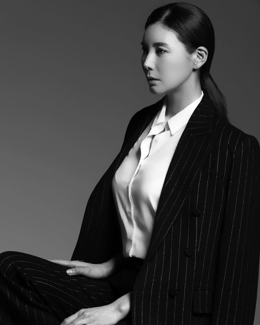 Black and white profile portrait of a woman wearing a pinstriped suit and white shirt.